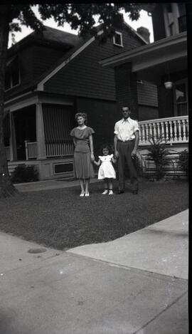 Iola Kingsborough et Harold Ross tenant la main d'une petite fille à l'extérieur