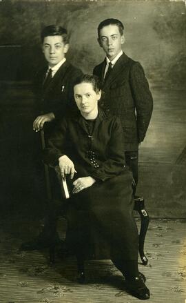 Photographie de deux jeunes garçons et d’une femme assise