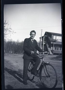 Lloyd Kingsborough sur une bicyclette devant une maison