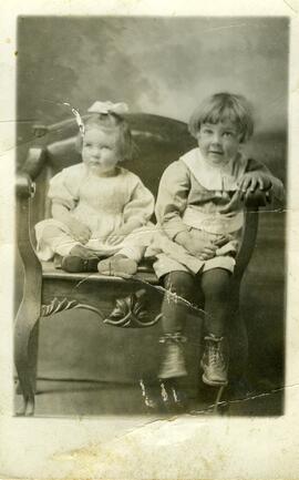 Photographie de deux jeunes enfants (assis tous deux sur une seule chaise)