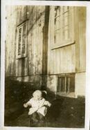 Un enfant non identifié assis sur une chaise devant un bâtiment