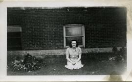 Alice Kingsborough assise au sol devant un bâtiment en brique