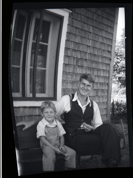 Clifford et Malcolm assis devant une maison