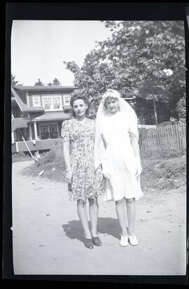Iola Kingsborough portant une robe et un voile blancs avec une jeune femme non identifiée