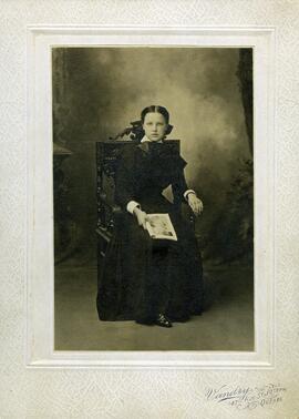 Photographie d’une jeune fille assise (une revue à la main)