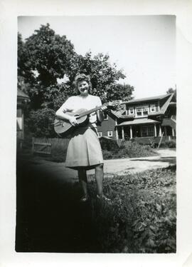 Iola Kingsborough tenant une guitare dans ses bras à l’extérieur