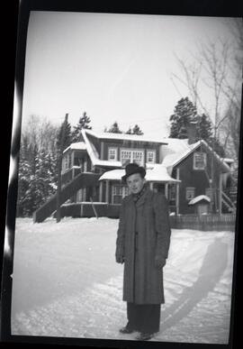 Un homme non identifié devant une maison en hiver