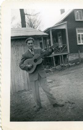 Malcolm Kingsborough tenant une guitare à l'extérieur